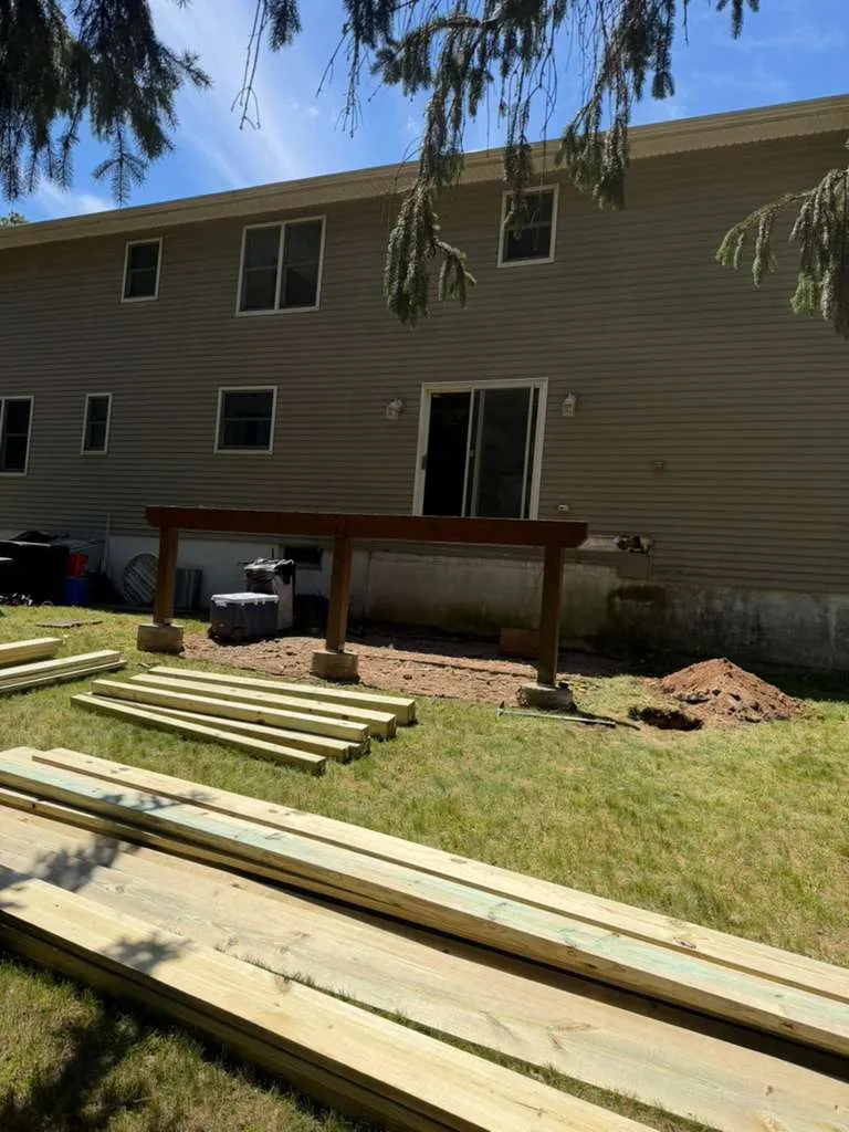 Deck Build Begins — Ledger board mounted to the home with footings dug and pressure-treated lumber staged, Bergen County NJ